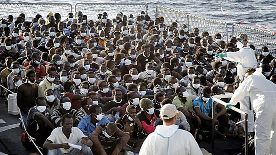 Von Bootem gerettete Flüchtlinge werden auf einem Schiff der italienischen Marine betreut.