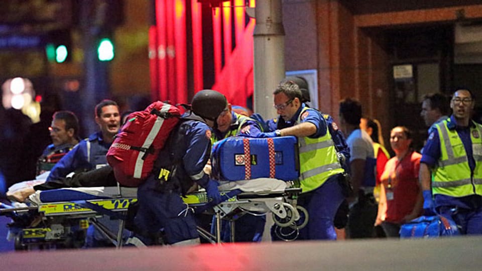 Nachdem die Polizei das Lindt-Café in Sydney gestürmt hat, werden die Geiseln von Rettungskräften geborgen.