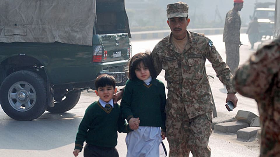 Ein Soldat in Peschawar begleitet einen Schüler und eine Schülerin, nachdem die pakistanische Armee die von Taliban besetzte Schule gestürmt hat.