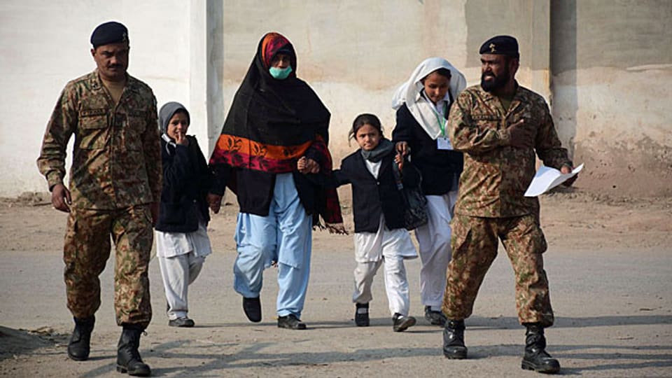 Schulkinder werden von Sicherheitskräften aus der Schule in Peschawar begleitet.