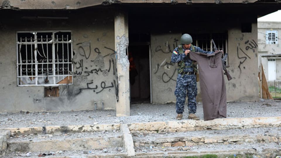 Ein Mitglied der kurdischen Armee mit einem Kleidungsstück eines IS-Kämpfers in einem provisorischen Basislager.