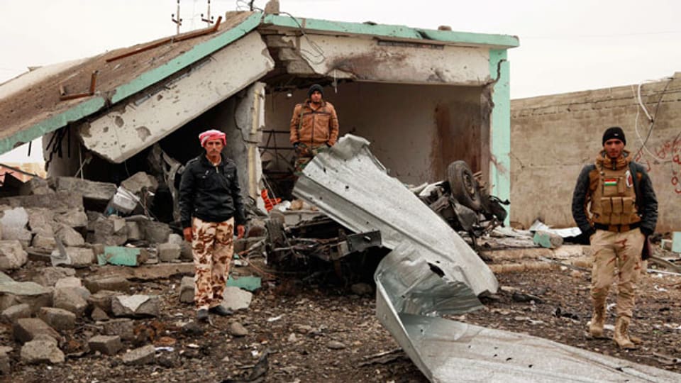 Kurdische Peschmergakämpfer vor einem zerstörten Gebäude in Zumar, im Sindschar-Gebirge, Irak. Aufnahme vom 18. Dezember 2014.