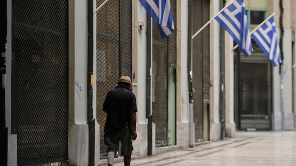 Ein obdachloser Mann in einer Einkaufspassage mit geschlossenen Läden in Athen.
