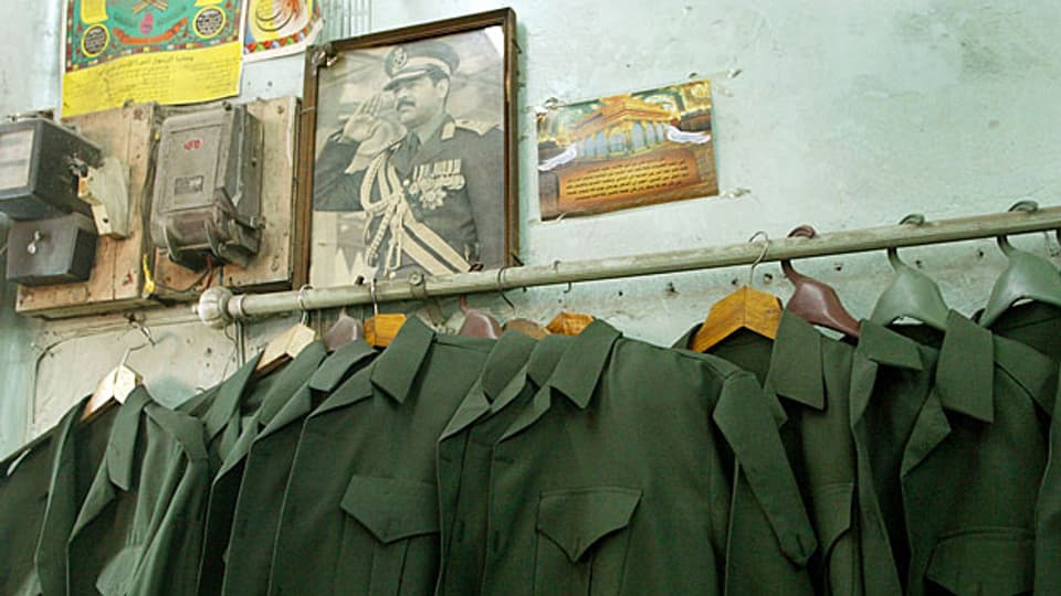 Irakische Armeeuniformen hängen an einer Kleiderstange unter dem Bild von Saddam Hussein, dem ehemaligen irakischen Diktator. Kommen sie zu neuen Ehren? Ein Bild vom Februar 2003.