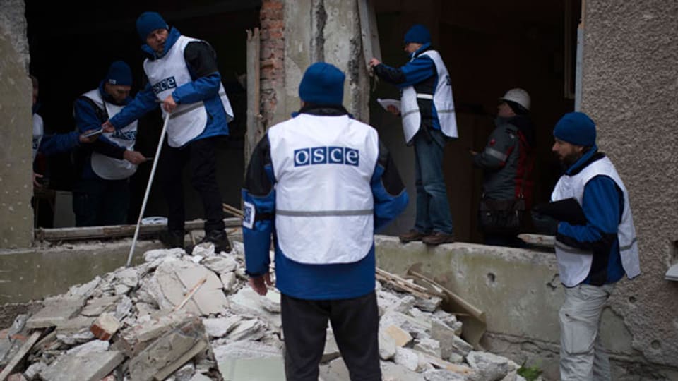 Unbewaffnete OSZE-Beobachter untersuchen ein bombardiertes Gebäude in der Ost-Ukraine.