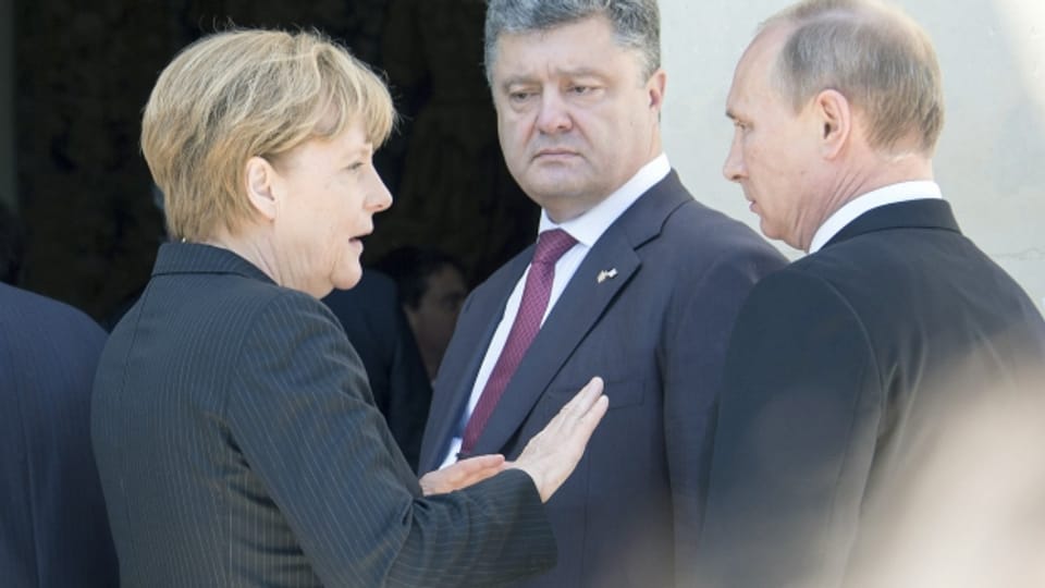 Die deutsche Bundeskanzlerin soll zwischen ihnen vermitteln: dem ukrainischen Präsidenten und Russlands Staatschef (im Juni 2014 anlässlich der 70-Jahr-Feiern zur Landung der Allierten in der Normandie).