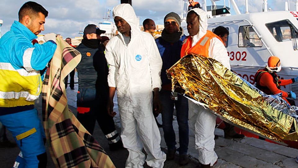 Einige Flüchtlinge, die überlebt haben, werden bei der Ankunft im Hafen von Lampedusa von Helfern betreut.