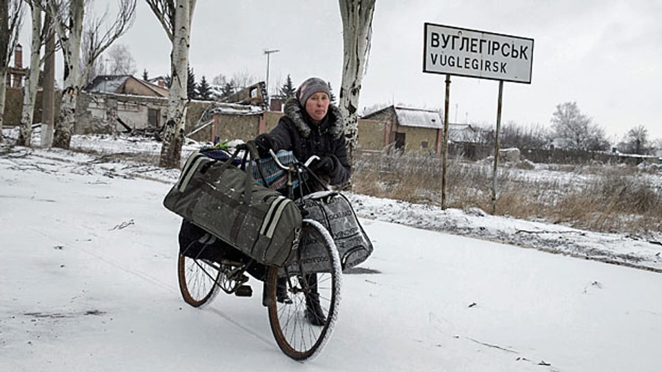 Die Zivilbevölkerung in der Ostukraine ringt Tag für Tag um Strom, Benzin, Wasser und Medikamente. Bild: Mit dem Fahrrad unterwegs in Vuglegirsk, einem Dorf in der Nähe der umkämpften Stadt Debalzewo.