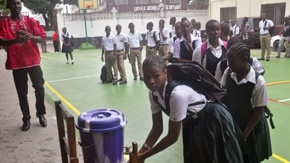 Schülerinnen und Schülder waschen sich die Hände vor einer Schule in Monrovia.