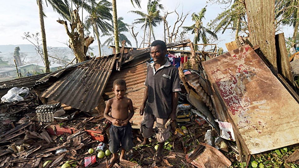Nach dem Zyklon «Pam» mit dem Leben davon gekommen: Ein Vater mit seinem Sohn vor dem zerstörten Heim in Port Vila, der Hauptstadt der Insel Vanuatu.