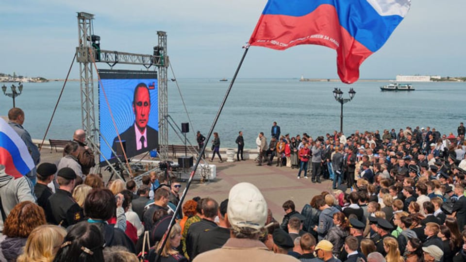 Menschen auf der Krim verfolgen eine Fernsehsendung mit dem russischen Präsidenten Wladimir Putin an der Strandpromenade in Sewastopol, Krim, am 17. April 2014.