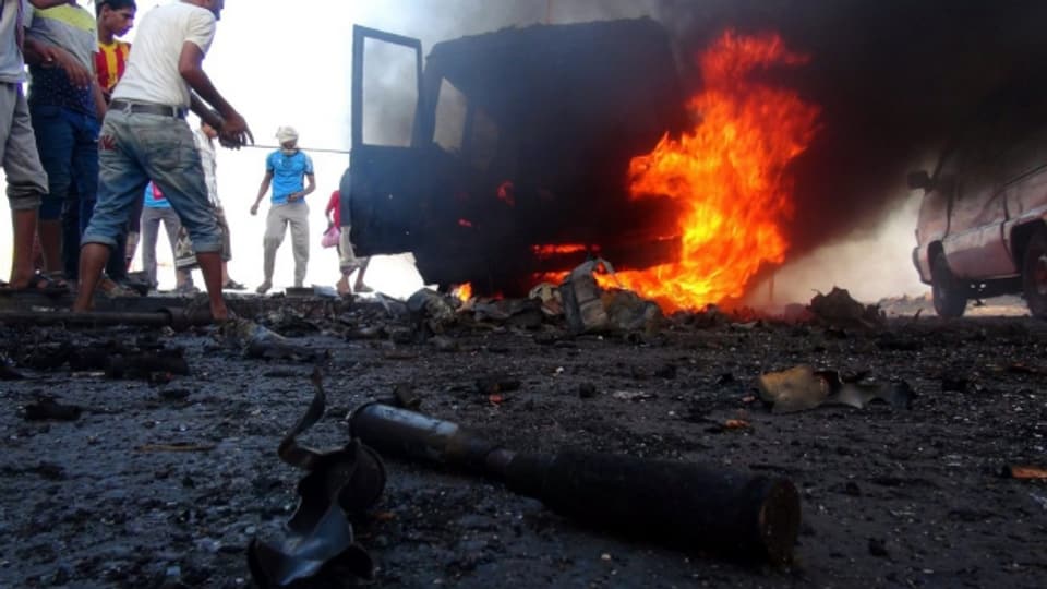 Jemeniten versammeln sich bei einem brennenden Auto der Huthi-Rebellen in der Hafenstadt Aden