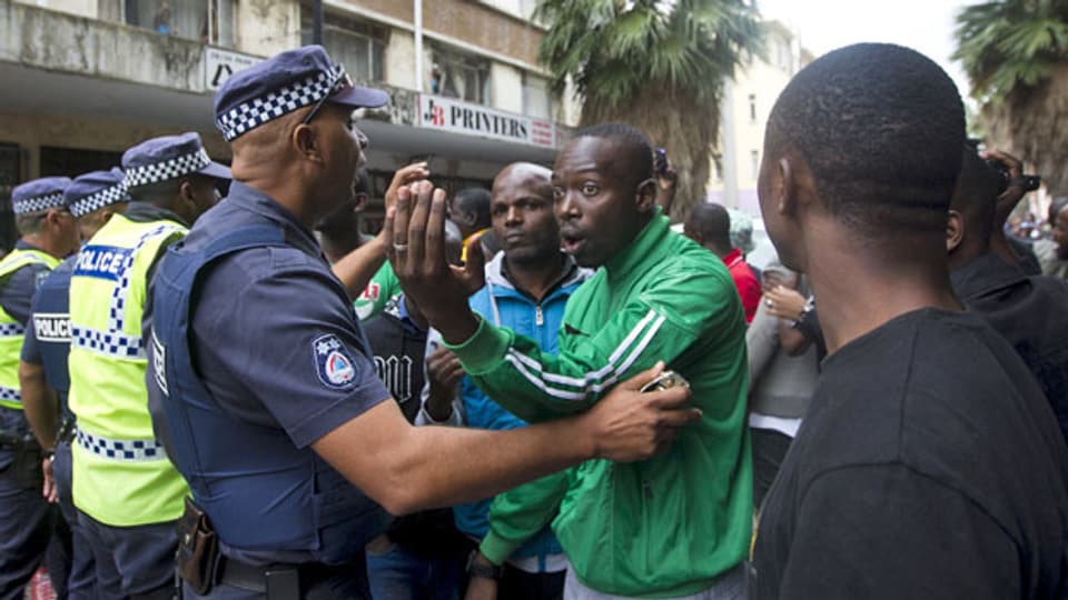 Polizisten versuchen in Durban, Südafrika, demonstrierende Männer zu beruhigen.