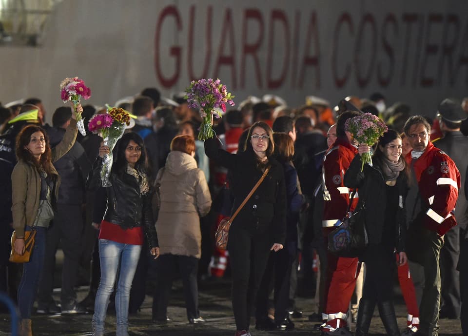 Aktivisten mit Blumensträussen in Catania bei der Ankunft von Überlebenden des Schiffsuntergangs.