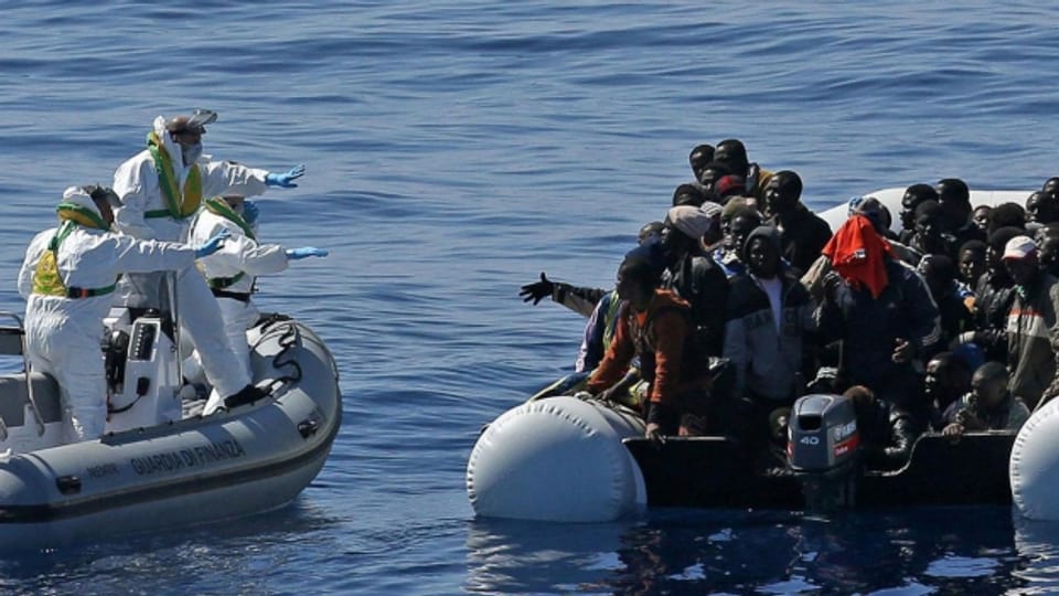 Ein Schlauchboot der italienischen Polizei kommt einer Gruppe von Flüchtlingen zur Hilfe.