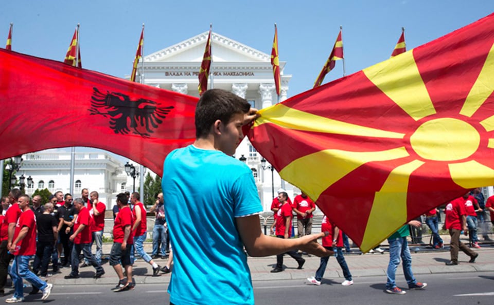 Ein Demonstrant schwenkt die mazedonische und die albanische Fahne vor dem Regierungsgebäude in Skopje