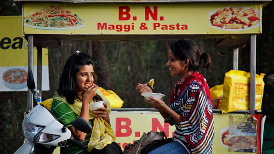  Indische Mädchen essen Nudeln in Ahmadabad, Indien. Die Maggi-Instant-Nudeln sind in Indien ungemein beliebt.