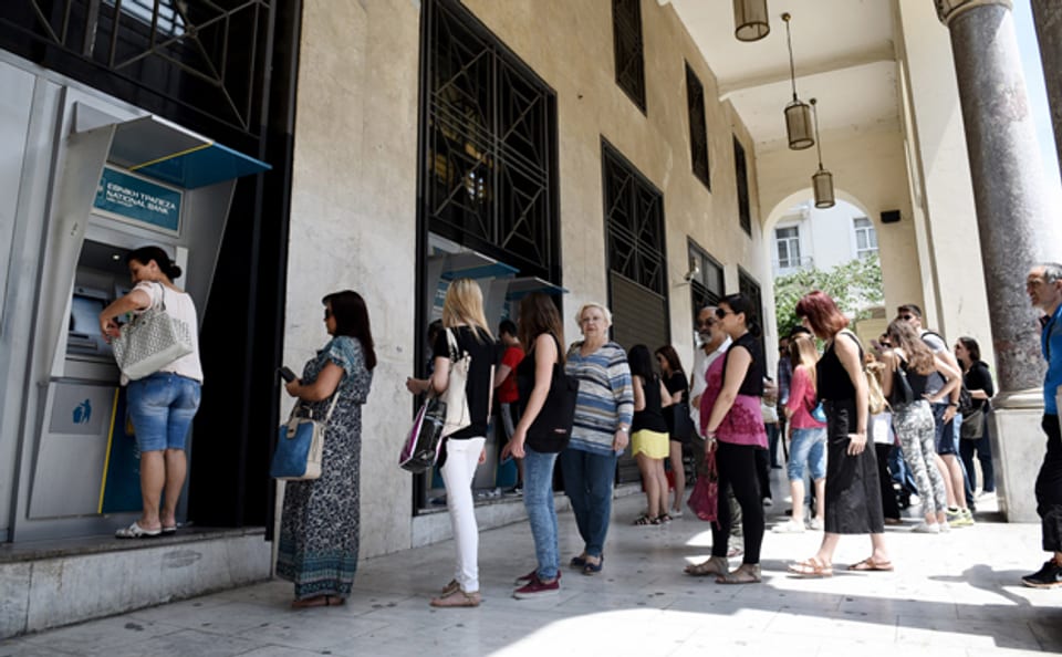 Griechinnen und Griechen in Thessaloniki versuchen an einem Automaten Geld abzuheben