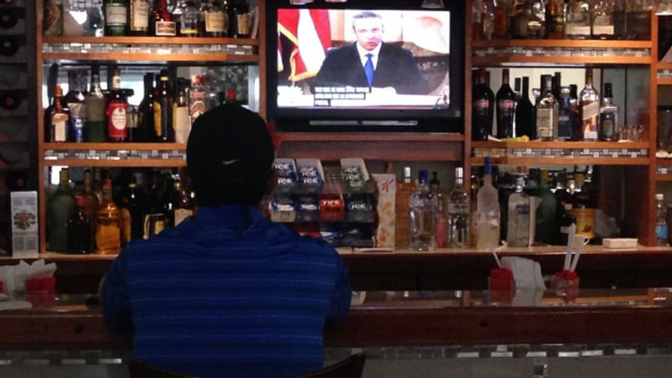 Ein Mann verfolgt die Rede des Gouverneurs zur Krise am Fernsehen.