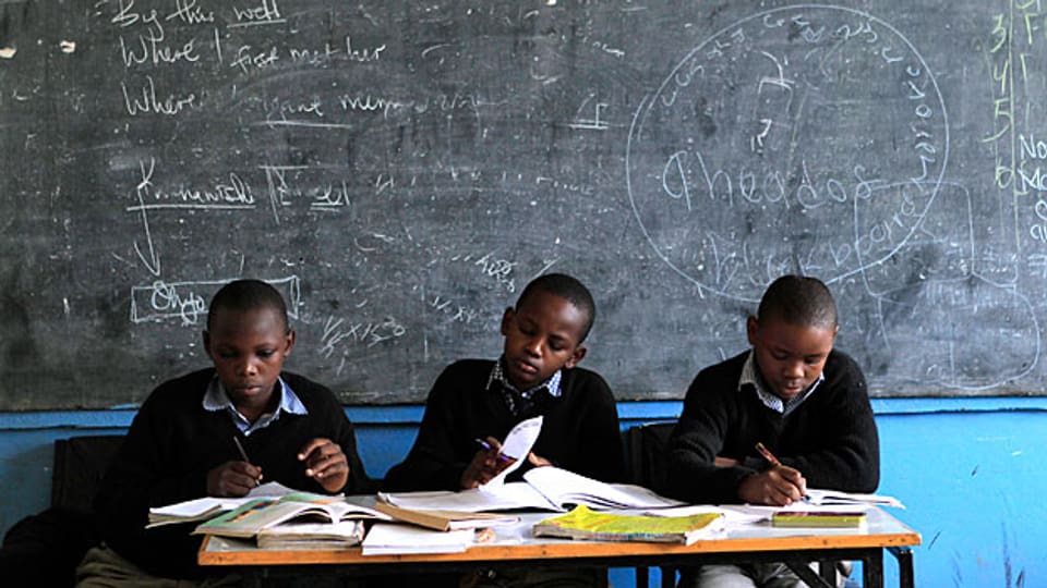 Drei Schüler einer Schule in Nairobi lernen am Tisch ihres Lehrers. Dieser ist abwesend - er streikt.
