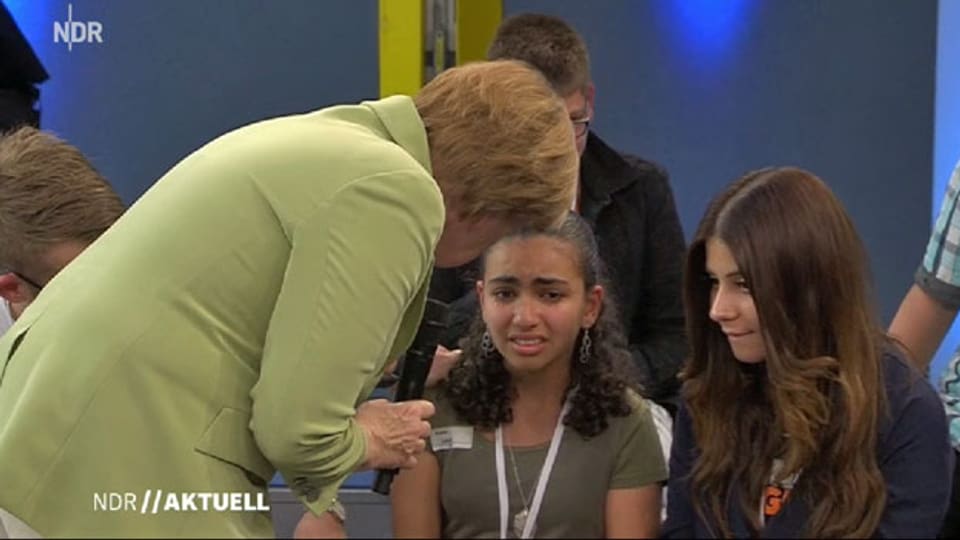 In einer Fernsehsendung verhält sich die deutsche Bundeskanzlerin Angela Merkel gegenüber einem syrischen Flüchtlingsmädchen ungeschickt.