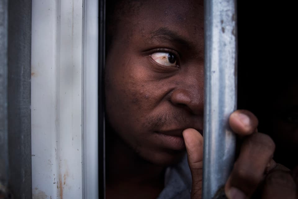 Ein illegaler Migrant in einem Käfig in Libyen