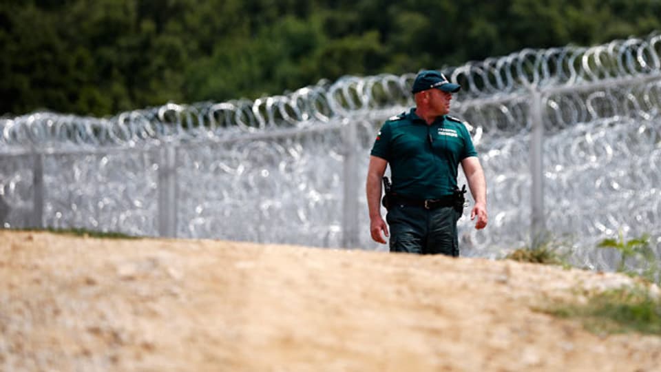 Ein bulgarischer Grenzpolizist kontrolliert die bulgarisch-türkische Grenze vor dem hochmodernen Stacheldrahtzaun.