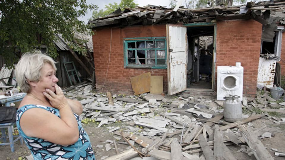 Eine Frau steht fassungslos vor ihrem zerstörten Haus am Stadtrand von Donetsk, am 16. August 2015.