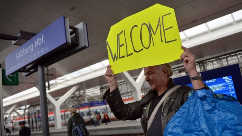Ein Passant heisst die Flüchtlinge auf der Durchreise nach Deutschland, am Salzburger Hauptbahnhof, am Samstag, 5. September 2015 mit einem Schild "Welcome", willkommen.
