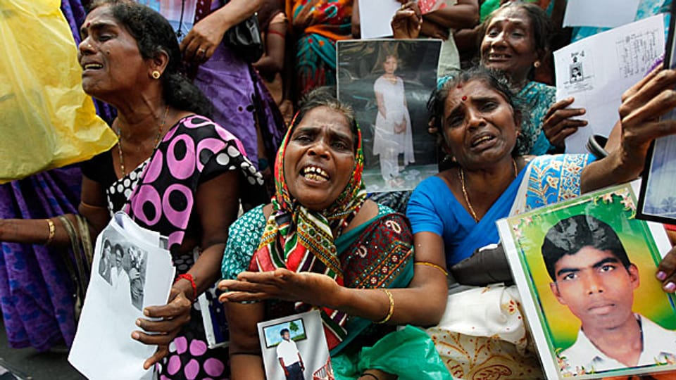 Fotos von Familienmitgliedern, die während des Krieges verschwunden sind. Tamilische Frauen im August 2013 an einer Veranstaltung in Jaffna.