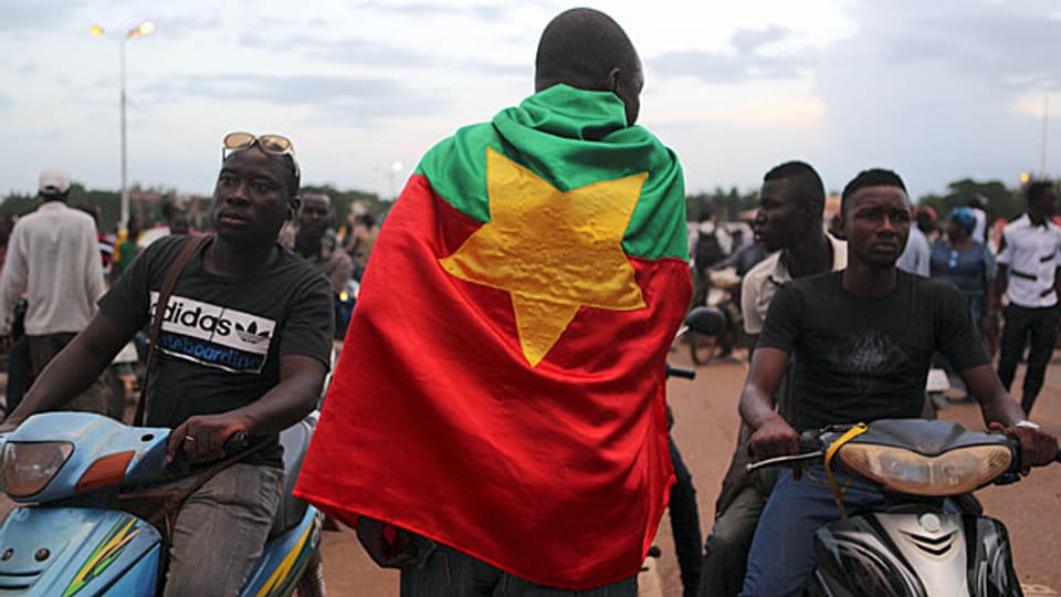 Burkina Faso war bis 1960 als Obervolta Teil Französisch Westafrikas. 1984 gab die Regierung dem Land den neuen Namen Burkina Faso, was mit «Land der Unbestechlichen» übersetzt wird. Der Demonstrant hat sich die Flagge von Burkina Faso um die Schultern gelegt.