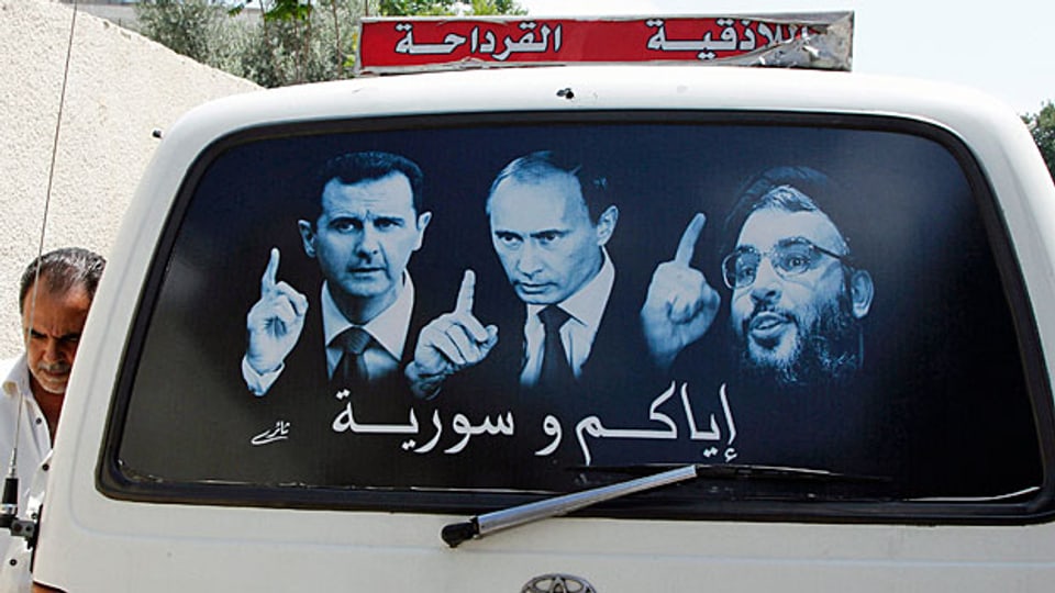 Putin will in New York die USA für seine neue Koalition gewinnen. Bild: Ein Kleinbus in Latakia zeigt ein Plakat mit dem syrischen Präsidenten Bashar al-Assad, dem russischen Präsidenten Putin und dem libanesischen Hisbollah-Führer Hassan Nasrallah.