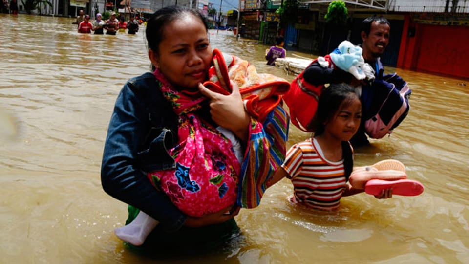 Menschen tragen ihre Habseligkeiten durch das Hochwasser in Java, Indonesien.