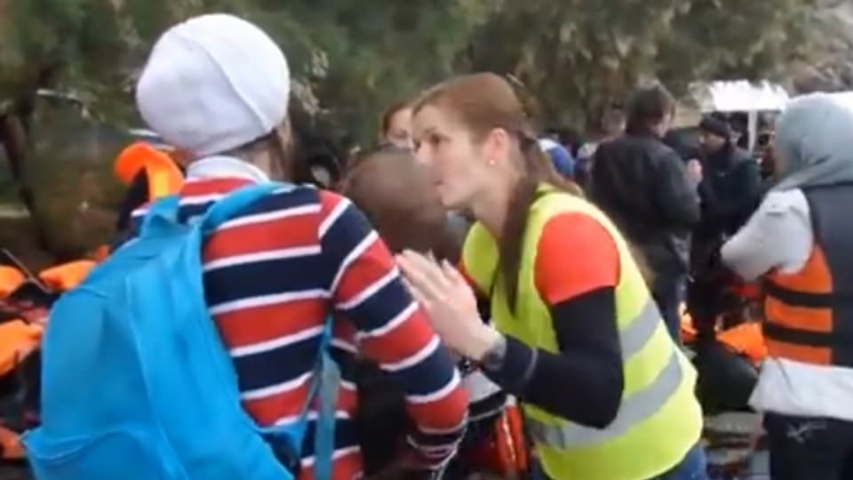 Eine Frau hilft einem Flüchtling am Strand von Lesbos.