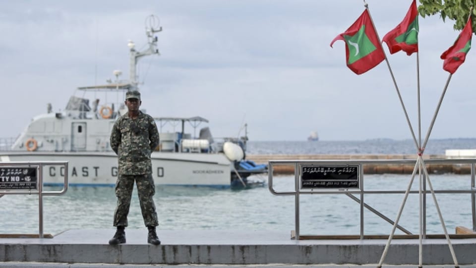 Ein Soldat steht Wache neben Flaggen der Malediven, wo für 30 Tage der Notstand gilt
