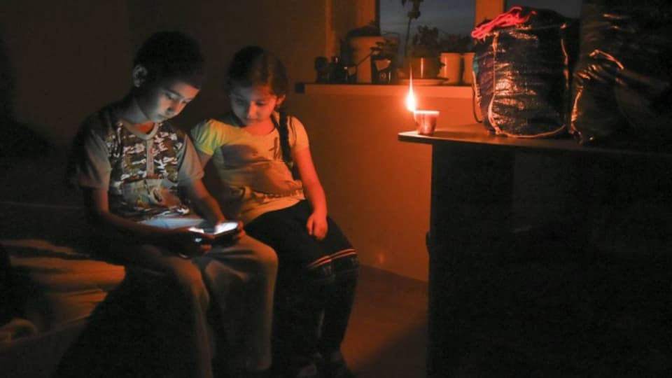 Die Bewohner auf der Krim kämpfen mit Stromproblemen: Kinder spielen bei Kerzenlicht mit dem Smartphone.