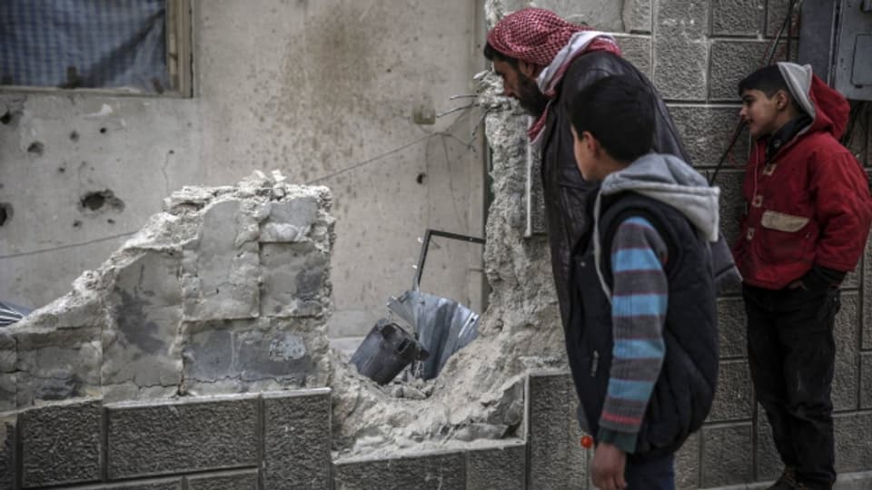 Syrer begutachten die Zerstörung nach einem Luftangriff in einem Vorort von Damaskus.