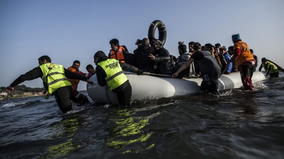Freiwillige Helfer ziehen das Flüchtlingsboot an den Strand