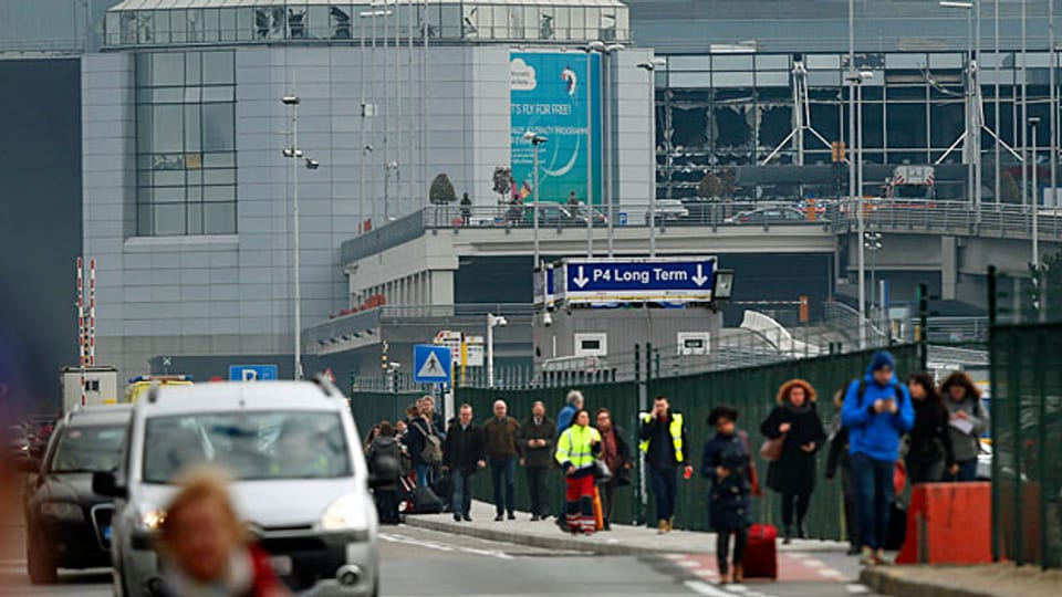 Auf dem Flughafen Brüssel und in zwei Metrostationen detonieren Sprengsätze, es gibt Tote und Verletzte; die Reisenden werden aus dem Flughafen evakuiert, Airlines streichen ihre Flüge, Züge und Metros stehen still.