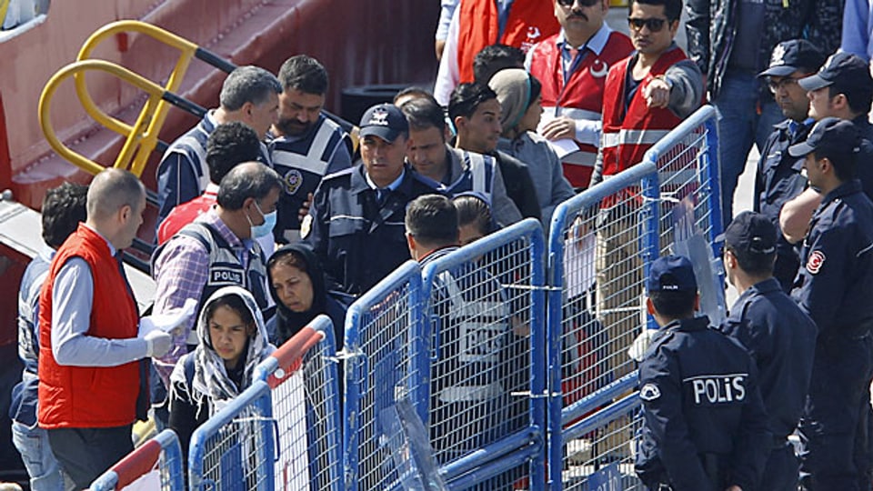 Türkische Polizisten eskortieren die ersten zurückgeschafften Flüchtlinge in Dikili vom Schiff.