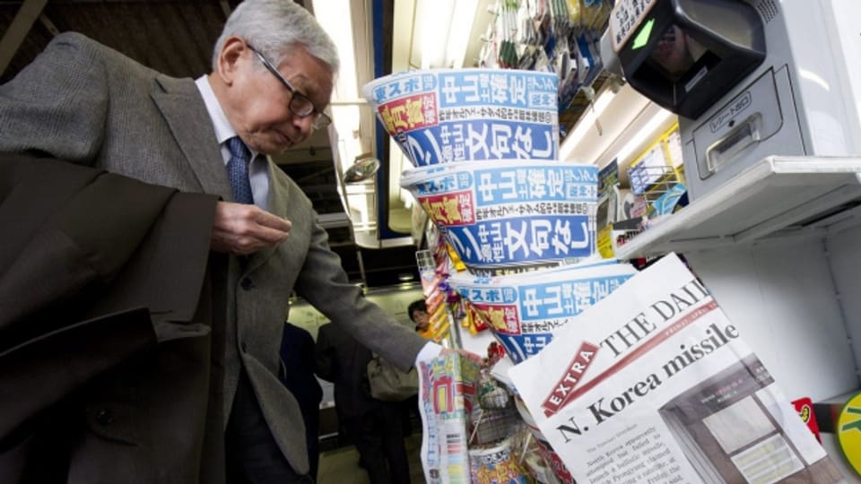 Ein Mann kauft sich in Japan eine Zeitung - die Journalisten sind unter Druck (2012).