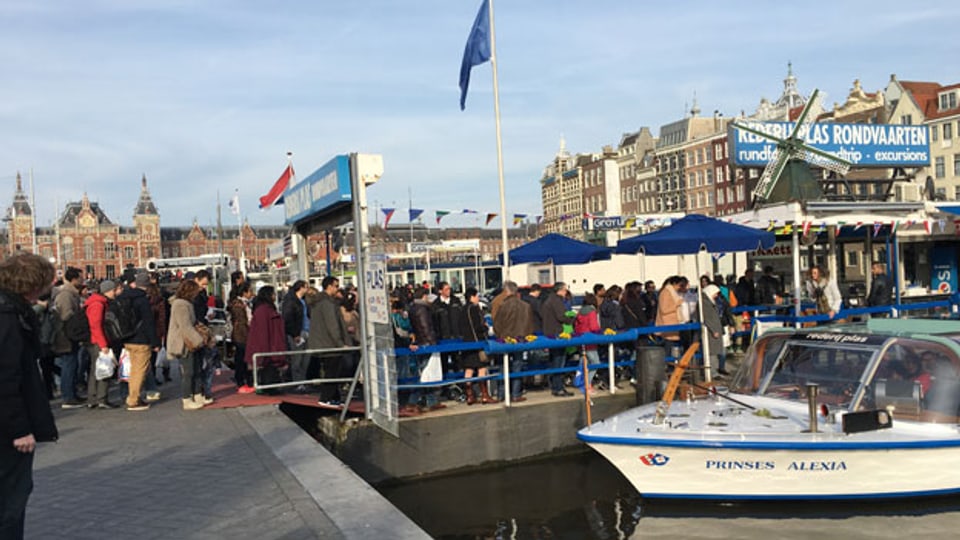 Warteschlangen, wo man hinschaut. Hier an der Bootsanlegestelle vor dem Hauptbahnhof, von wo aus die Touristen Rundfahrten durch Amsterdams Grachten unternehmen.