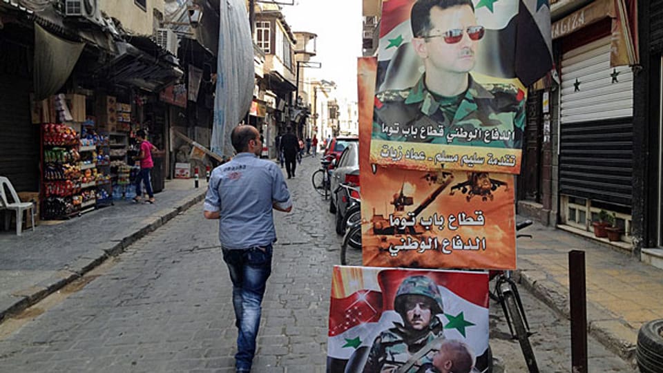 Patriotische Slogans: Assad wird auf Plakaten als Beschützer des Vaterlands gefeiert. Das Regime bezahlt auch im sechsten Kriegsjahr noch Löhne und Renten, hält die Institutionen aufrecht, so gut es geht. Der Staat verschuldet sich dafür tief.