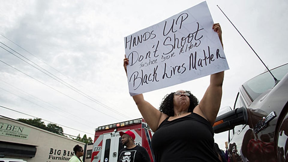 Nach einer Gedenkfeier für den erschossenen Alton Sterling protestiert eine Frau mit einem Transparent: «Hands up. Don't shoot. Black Lives Matter.»