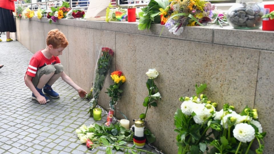 Eine Knabe legt Blumen in der Nähe des Tatorts in München nieder.