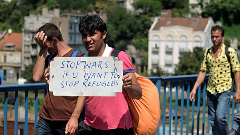 «STOP WARS IF U WANT TO STOP REFUGEES», steht auf dem kleinen Plakat eines Mannes in einer Flüchtlingsgruppe in Belgrad.
