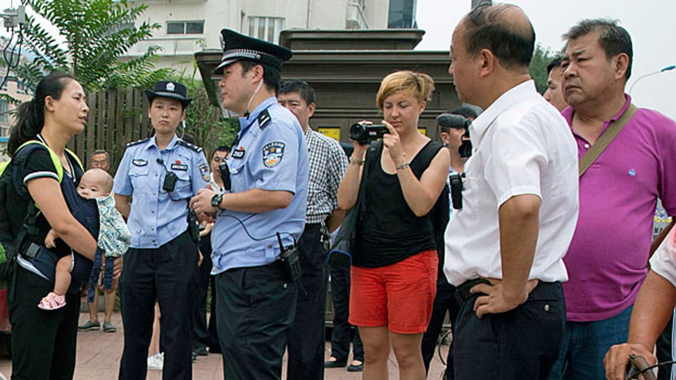 Die Ehefrau eines der verhafteten Bürgerrechtler, wird von einem Polizisten befragt; sie wartet mit anderen Aktivisten auf das erste Urteil.