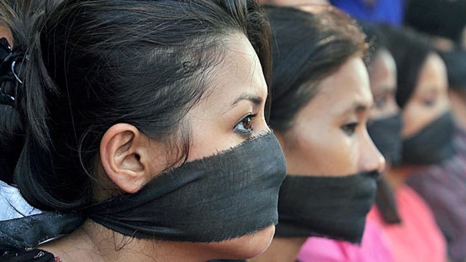 Zwei Frauen mit schwarzen Bändern vor dem Mund, protestieren gegen die Massenvergewaltungen in Indien.