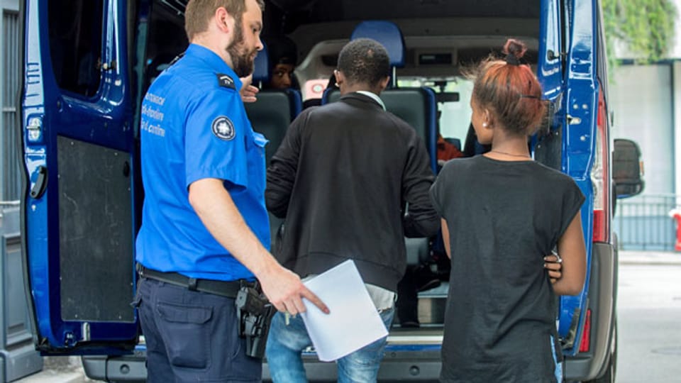 Ein Grenzwächter begleitet, am Bahnhof in Chiasso Flüchtlinge. Sie wollten mit einem Bus nach Deutschland gelangen, konnten aber an der Schweizer Grenze nicht weiterreisen, da sie keinen Pass besassen. Archivaufnahme vom Juli 2016.