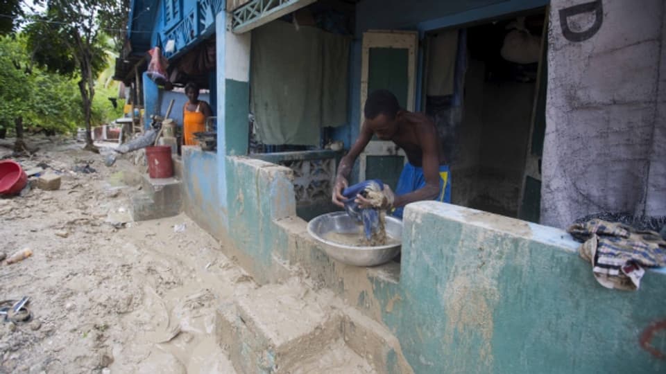 Ein Mann räumt Schlamm weg vor seinem Haus in Grand Goave in Haiti.